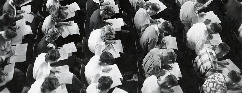 black and white image of rows of students taking a test