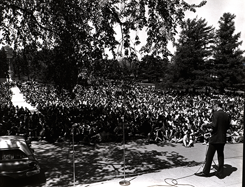 Image of student rally on campus, showing a speaker from behind